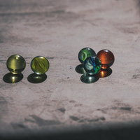 木の表面に転がるカラフルなビー玉と映る影の写真