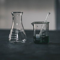 怪しい色の液体が入った実験中のビーカーと理科器具の写真