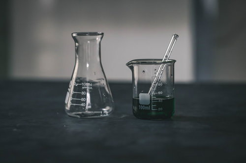 怪しい色の液体が入った実験中のビーカーと理科器具