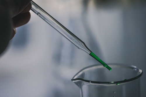 スポイトで採取する緑色の液体と試験管を使用した実験