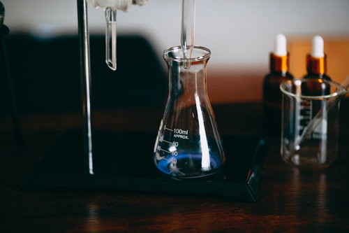 液体を注ぐ三角フラスコの容器、ドロッパーで青い液体が注がれる実験風景