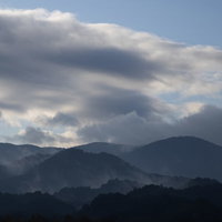 雨上がりにガスがかかる山々の夕暮れ時の山脈風景の写真
