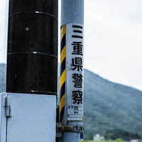 電柱に貼られた三重県警察の看板と地域の風景の写真