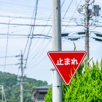 赤い三角形の止まれの標識は電柱に設置された道路交通標識の写真
