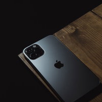 ケース未装着でテーブル端に置かれたシルバーiPhoneの写真