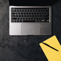 ノートパソコンと黄色いメモ帳を並べたデスク上の配置の写真