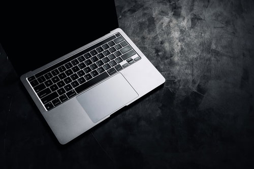 照明が当てられたシルバーのノート型パソコン