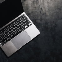 グレーの背景に置かれたシルバーのノートパソコンの写真
