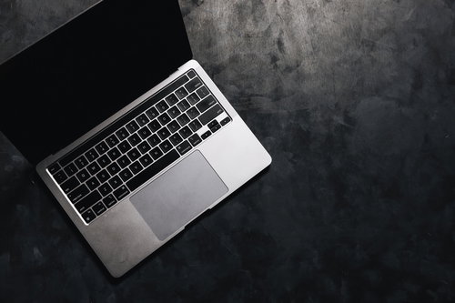 グレーの背景に置かれたシルバーのノートパソコン