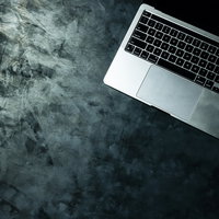 粗いコンクリート調テーブル上に置かれたMacBookの写真