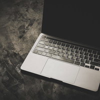 暗い床に置かれた光に照らされるノートPCの写真