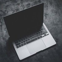 暗い床に置かれたノートパソコンの液晶から伸びる影の写真