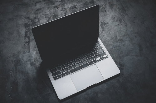 暗い床に置かれたノートパソコンの液晶から伸びる影