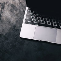 ノートパソコンのキーボードに伸びる影と光の写真