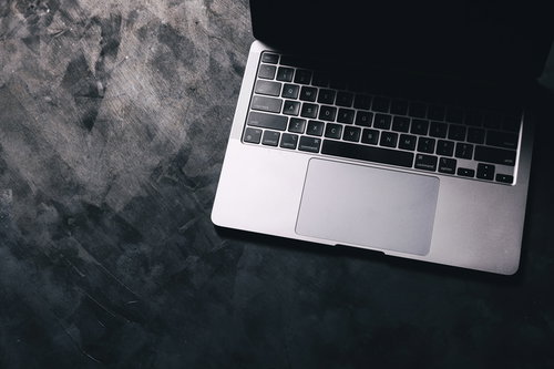 ノートパソコンのキーボードに伸びる影と光