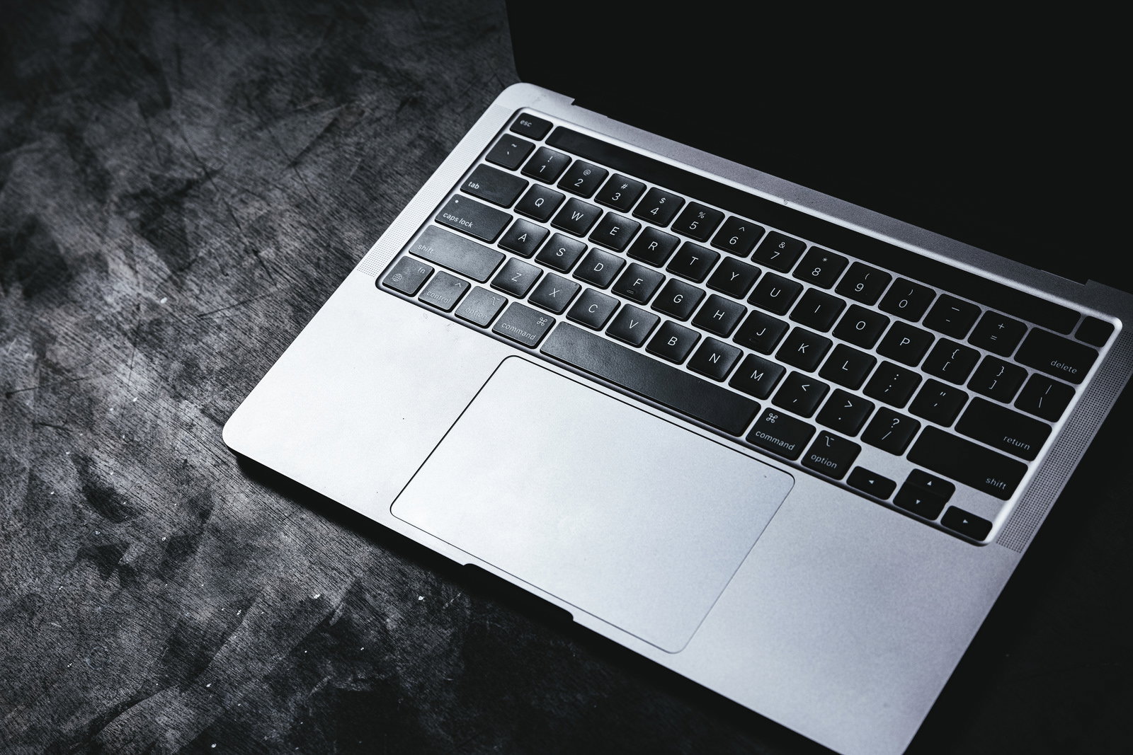 グレーの布地の上に置かれたシルバーMacBookのキーボードとタッチパッド