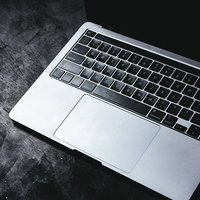 シルバーのMacBookのタッチパッドを照らす照明の写真