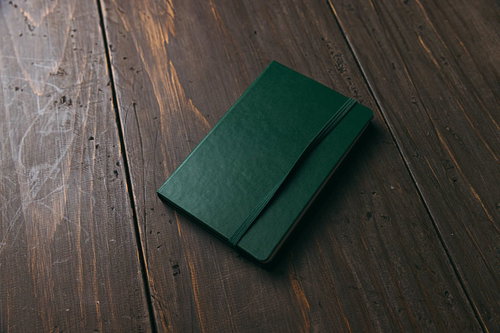 木目調のフローリングに置かれた緑色の手帳
