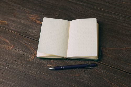 グリーンの手帳とネイビーボールペン、白紙のドット方眼ノート