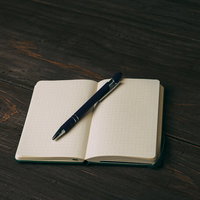 白紙の手帳に置いたボールペン、ドット罫ノートのデスクの写真