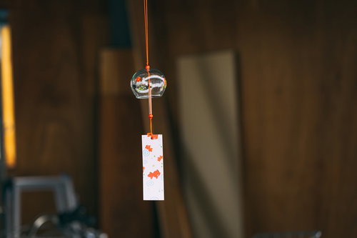 軒に吊るしたガラス風鈴とオレンジの紐、白い短冊