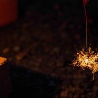 夜間に燃える線香花火のパチパチと散る火花の写真