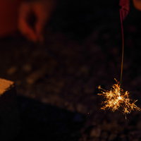 夜間の庭で光る線香花火の儚い思い出、黄金色の火花が散る夏の風物詩の写真