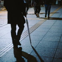 夜間の駅前で傘を持った帰り道、タイル通路を歩く人々の写真