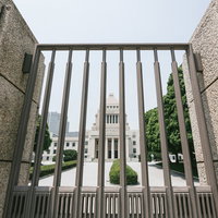 石造りの柵越しに見える国会議事堂と緑の景観の写真
