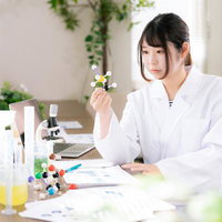 分子模型を手に取り、真剣な表情で観察する研究者の女性の写真