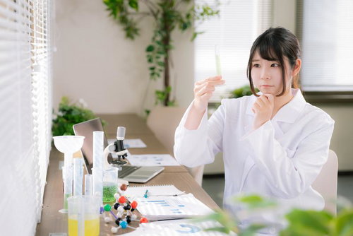 試験管を手に取り中身を観察する白衣を着た女性研究者
