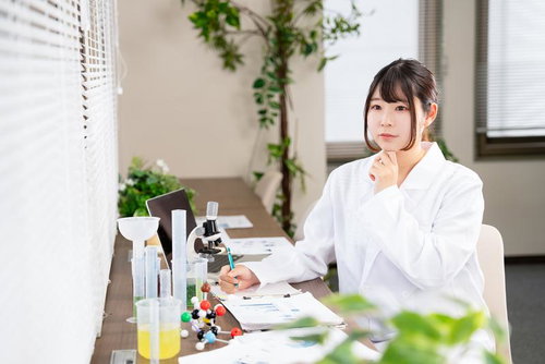 研究室で顎に手を当て考え込む白衣を着た女性研究者