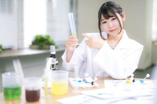 研究室で実験する白衣を着た若い女性研究者と顕微鏡