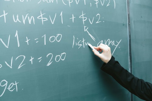 黒板に書かれたプログラミングコードと講師の手