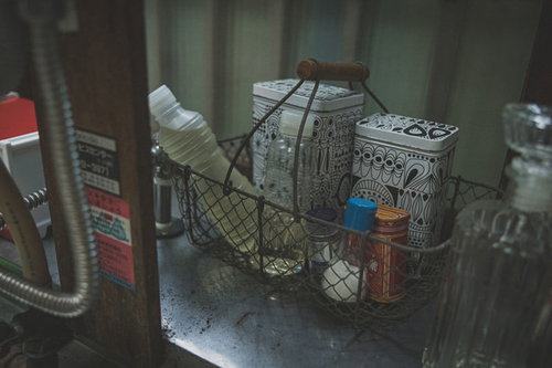 昭和レトロな台所の棚に並ぶ調味料の瓶と容器