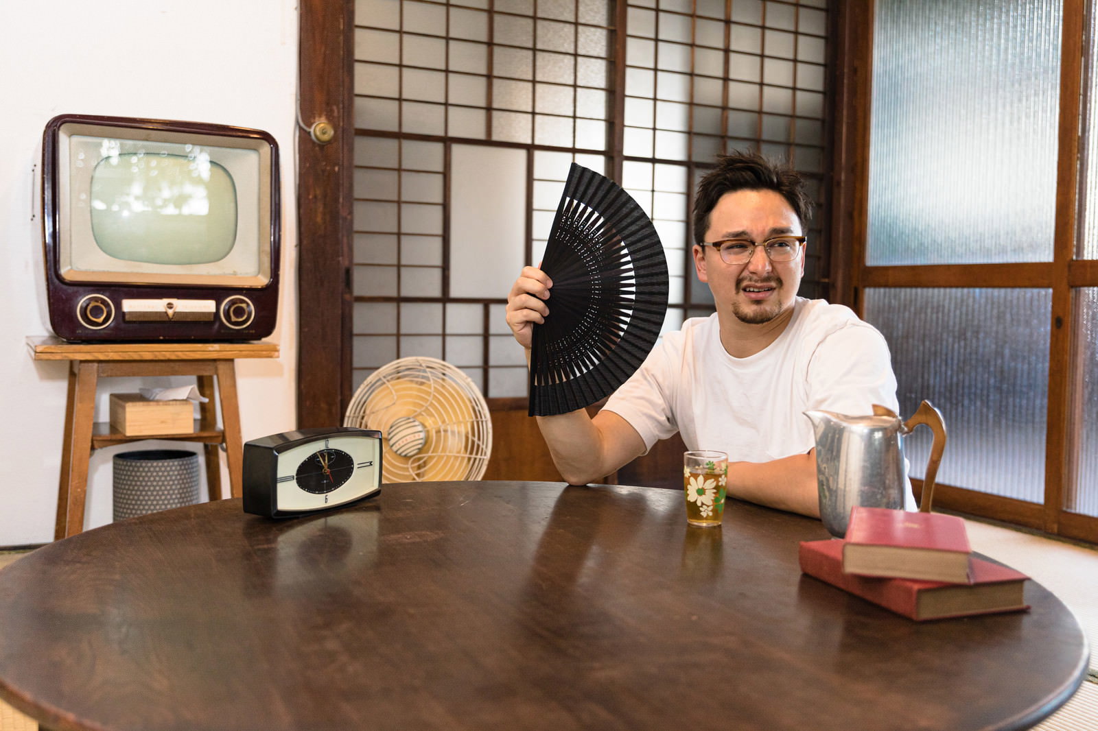 古民家の和室でチャブ台に座り扇子で涼を取る外国人男性［モデル：Max_Ezaki］