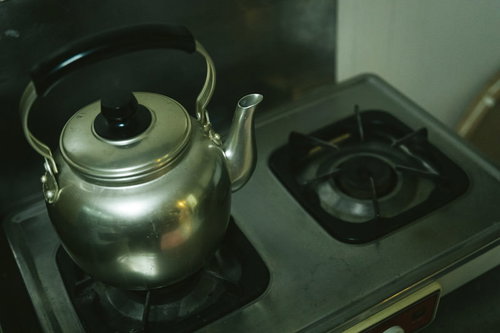 ガス台に置かれたステンレス製やかんの調理風景