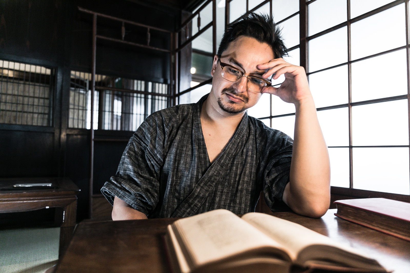 畳の書斎で甚平を着た男性が本を読んでいる［モデル：Max_Ezaki］