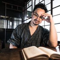 古民家の書斎で本を読む甚平姿の男性の読書風景の写真