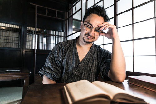 古民家の書斎で本を読む甚平姿の男性の読書風景