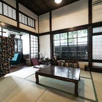 古民家の和室6畳に囲炉裏と低いテーブル、格子窓の写真