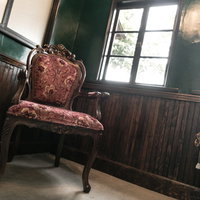 洋館の緑の壁に映える赤い花柄のアンティーク椅子の写真