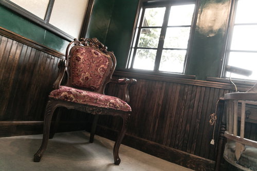 洋館の緑の壁に映える赤い花柄のアンティーク椅子