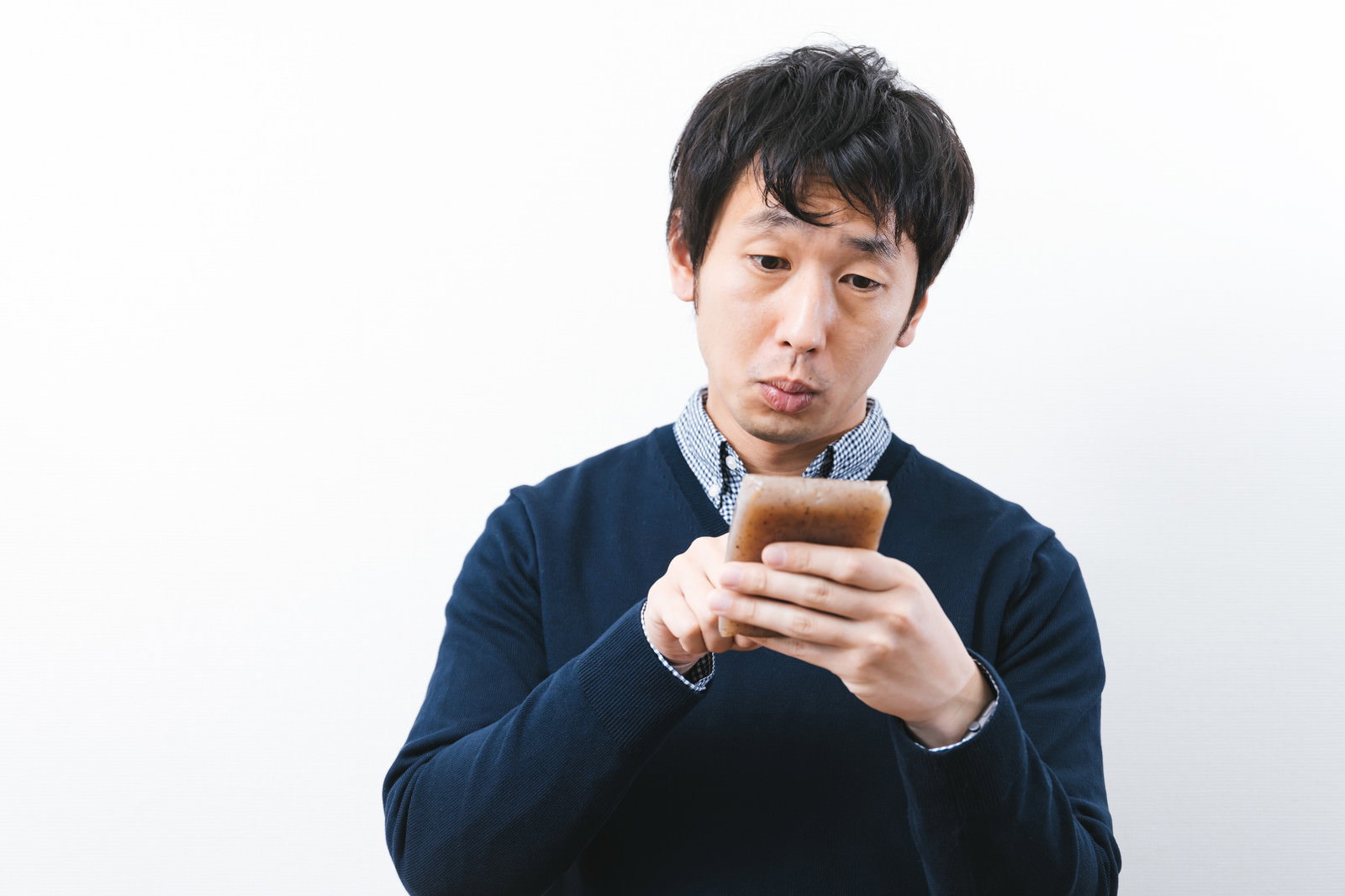 デスクでスマホ型こんにゃくを手に持つ人［モデル：大川竜弥］