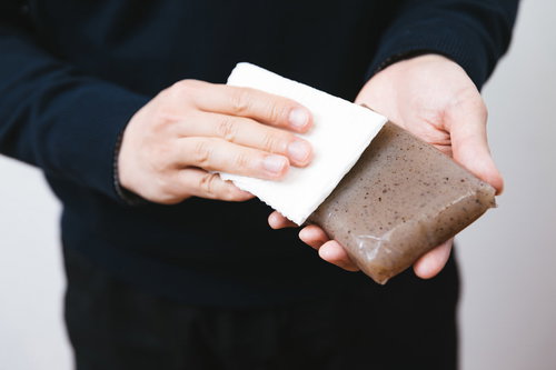 こんにゃくの表面の汚れやヌメリを拭き取る男性の手元