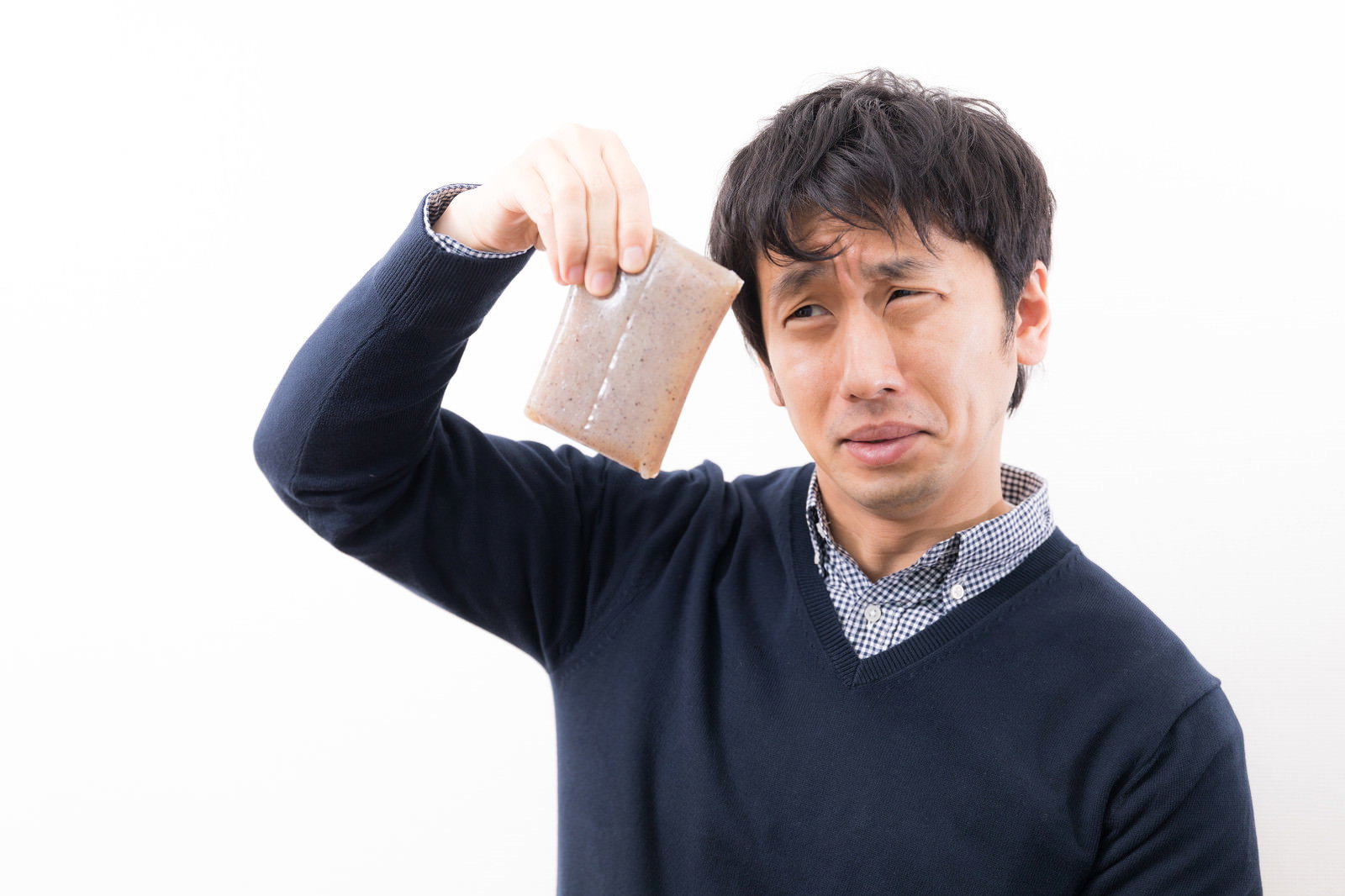 こんにゃくの異臭に鼻をつまんで嫌な顔をする男性［モデル：大川竜弥］