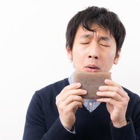 こんにゃくの生臭いにおいを嗅ぐ男性の食品評価の写真