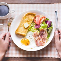 朝食はコーヒーとバターパン、目玉焼きにベーコンとサラダの写真