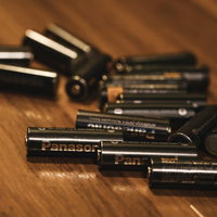 木目テーブルに散らばる充電式乾電池（単3形）の写真