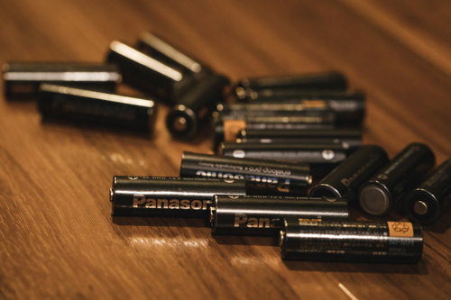 木目テーブルに散らばる充電式乾電池（単3形）